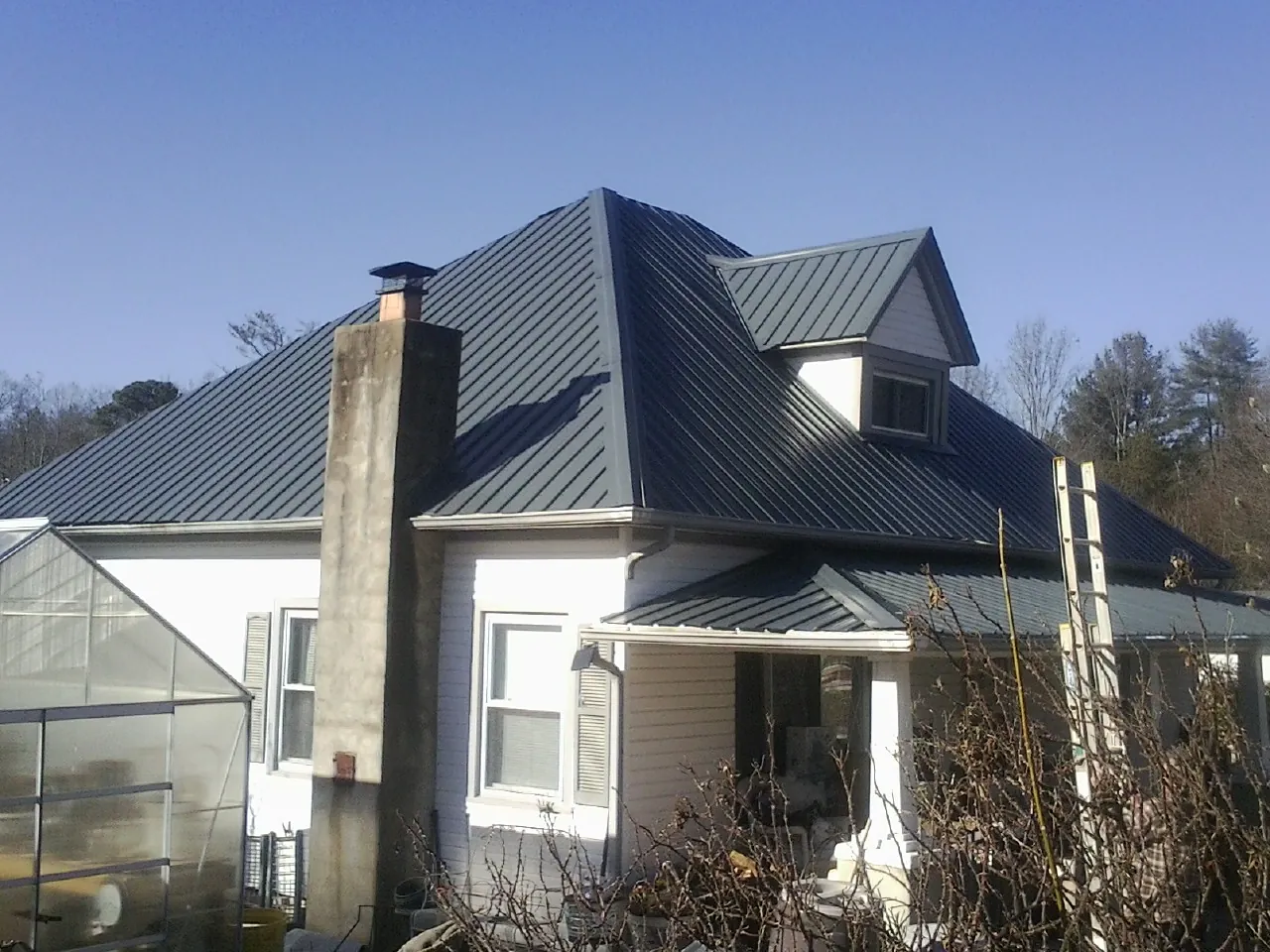 Dark blue standing seam metal roof on a white farmhouse with dormer — Slate & Tile Roof Repair by Roofing Brothers in Killeen