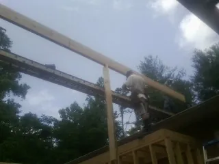 Carpenter setting a ridge beam over a new addition frame — Ice Dam Removal by Roofing Brothers in Killeen