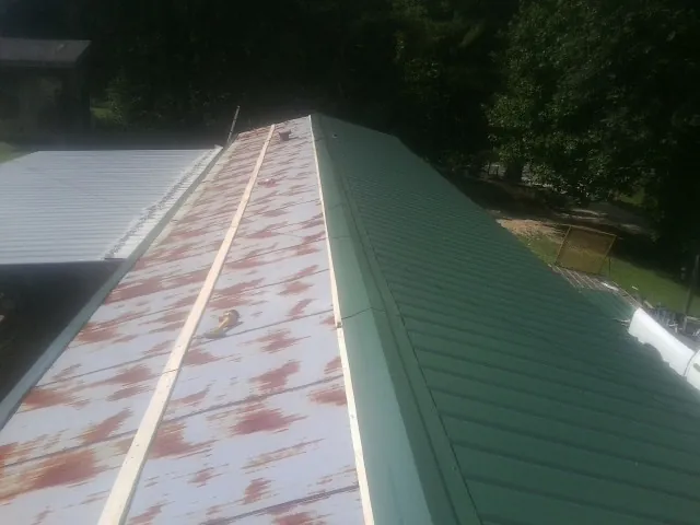 Old rusted panels beside newly installed green metal roofing — Wind Damage Roof Repair by Roofing Brothers in Killeen