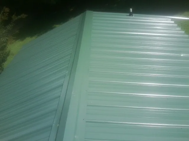 New green metal panels meeting at the ridge of a roof — Flat Roof Repair work by our crew in Killeen