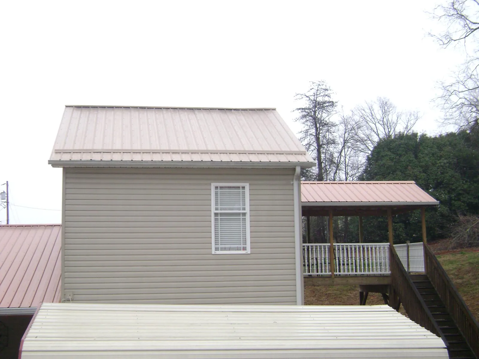 Tan metal roofs on a two story addition and attached porch, from a Roof Replacement job in Killeen